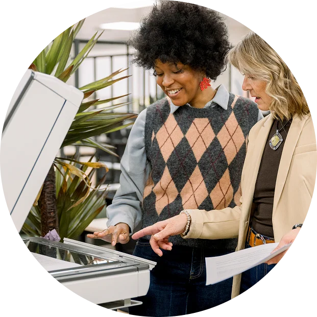 Two women using a copy machine and talking